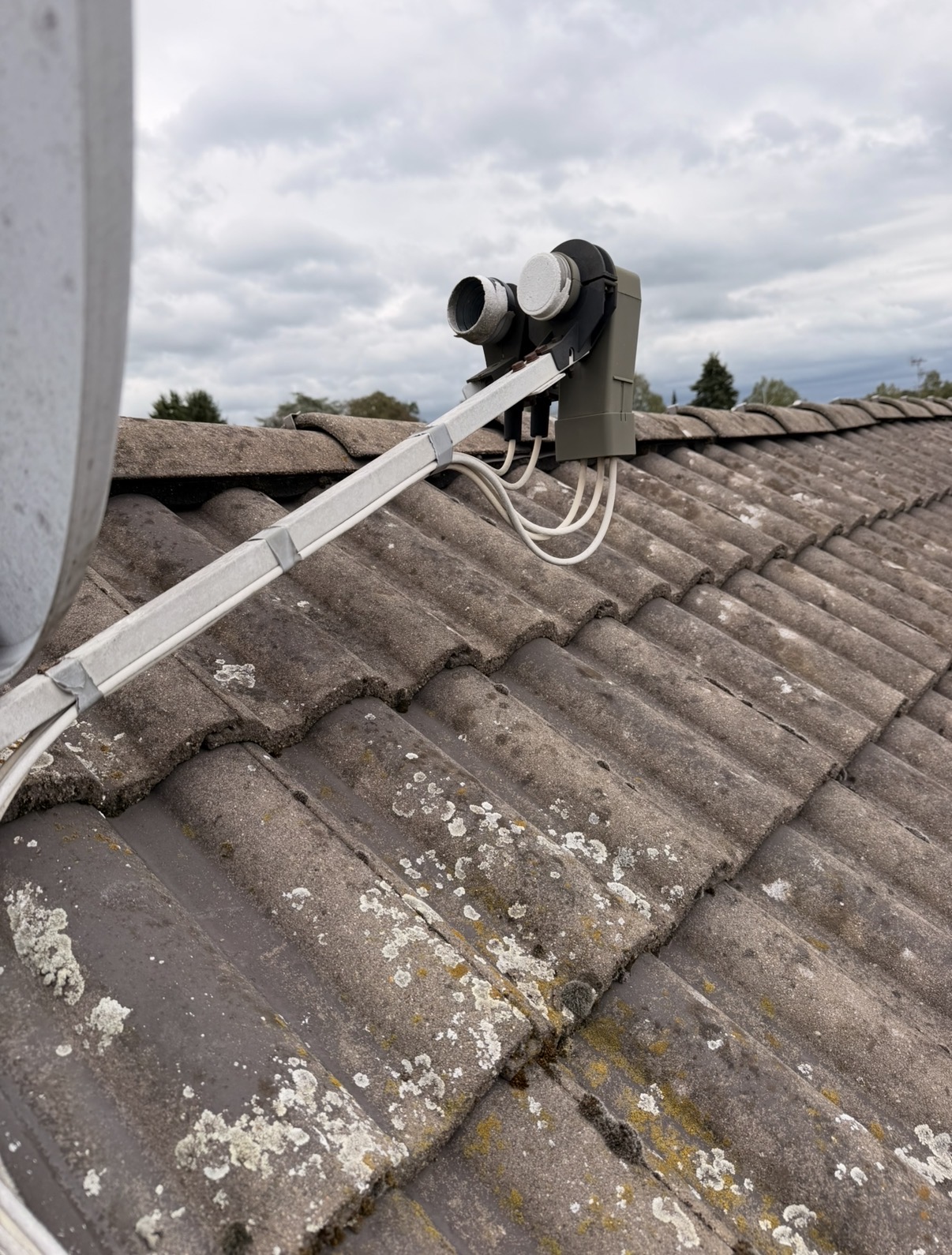 Ältere Satellitenanlage auf einem Hausdach mit sichtbaren Witterungsspuren