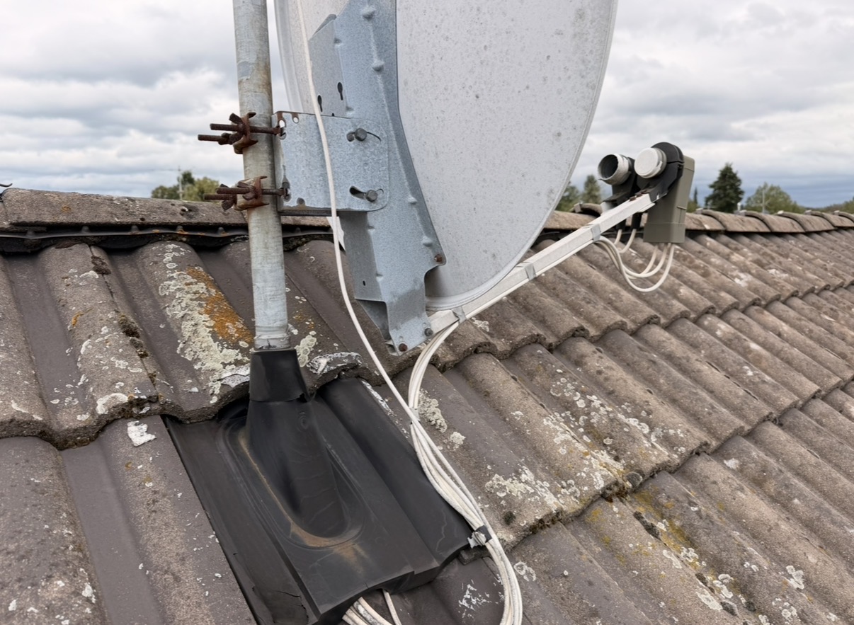 Satellitenschüssel auf dem Dach mit gealterten Kabeln und beschädigter Dachdurchführung